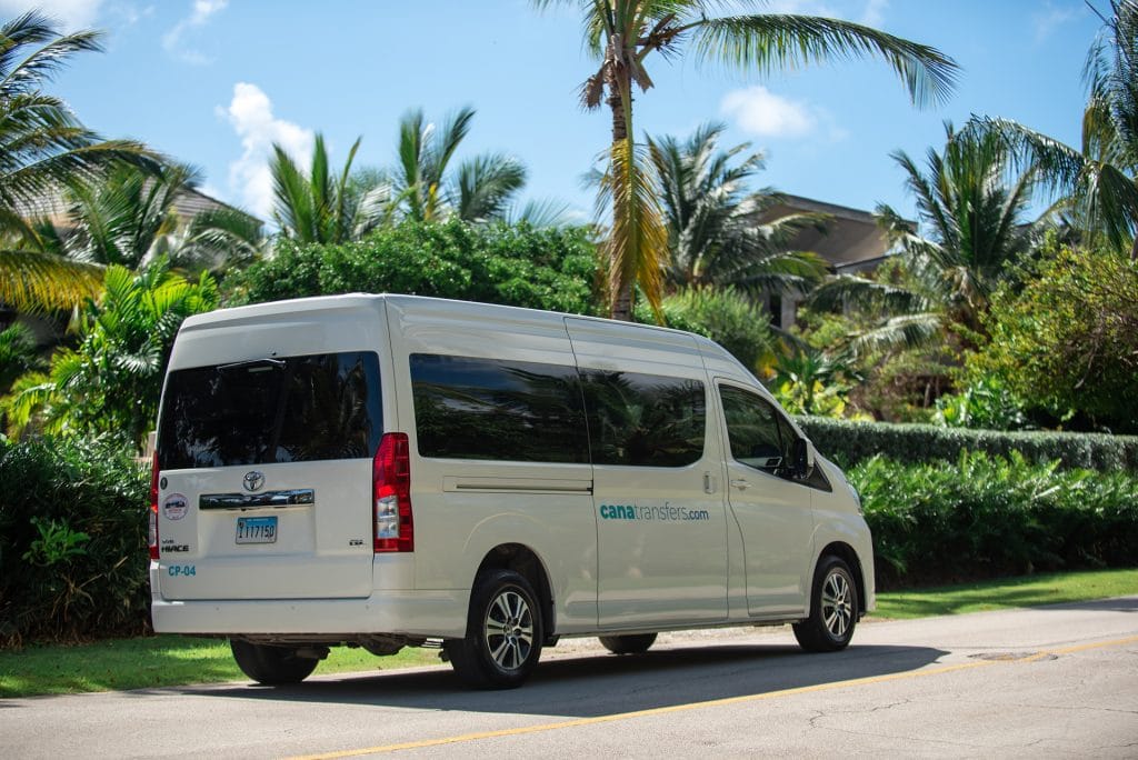Rear three-quarter view of a white Toyota Hiace of Cana Transfers surrounded by palm trees in Punta Cana