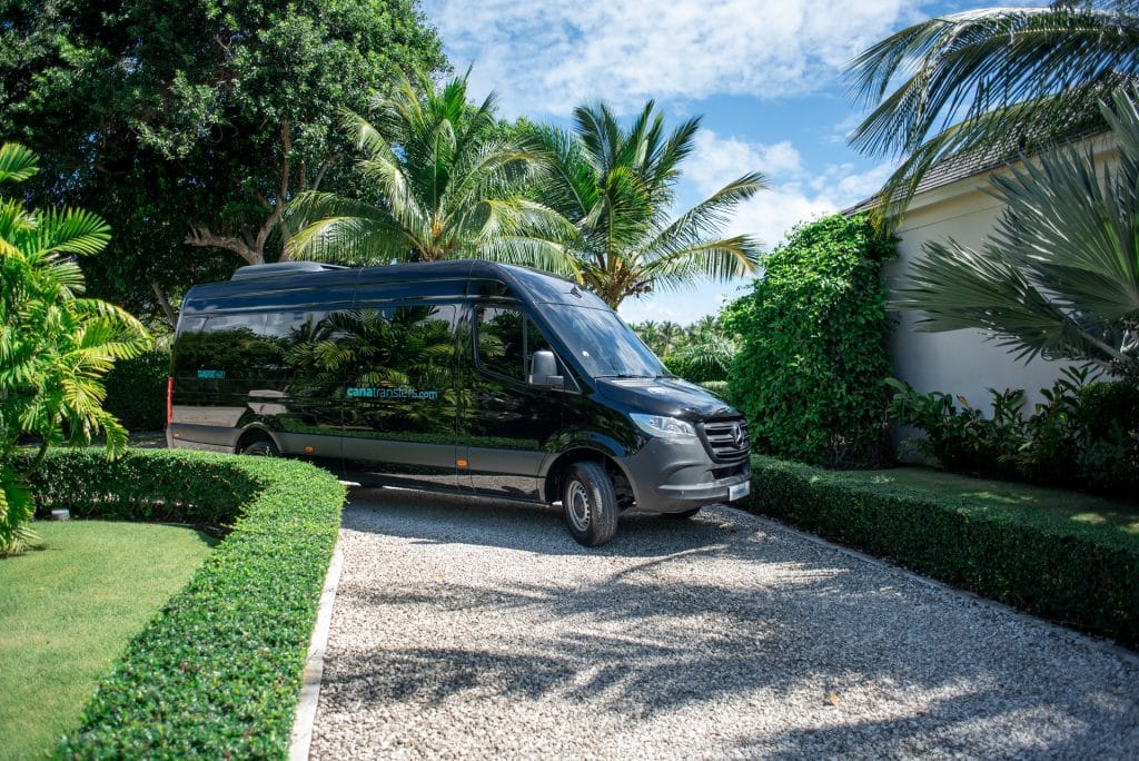 Black Mercedes-Benz Sprinter minibus of Cana Transfers parked among palm trees in Punta Cana