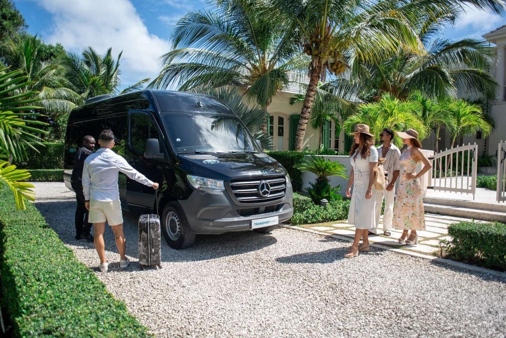 Group of guests with a black Cana Transfers minibus among palm trees in Punta Cana