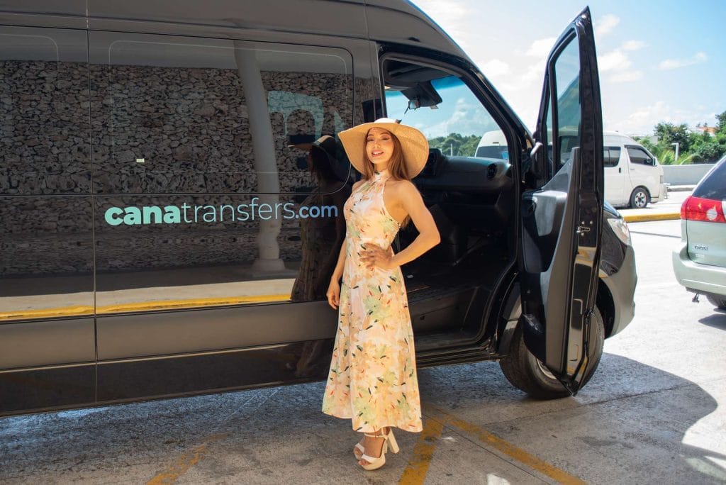 Happy customer in front of a Cana Transfers van with the company logo in Punta Cana
